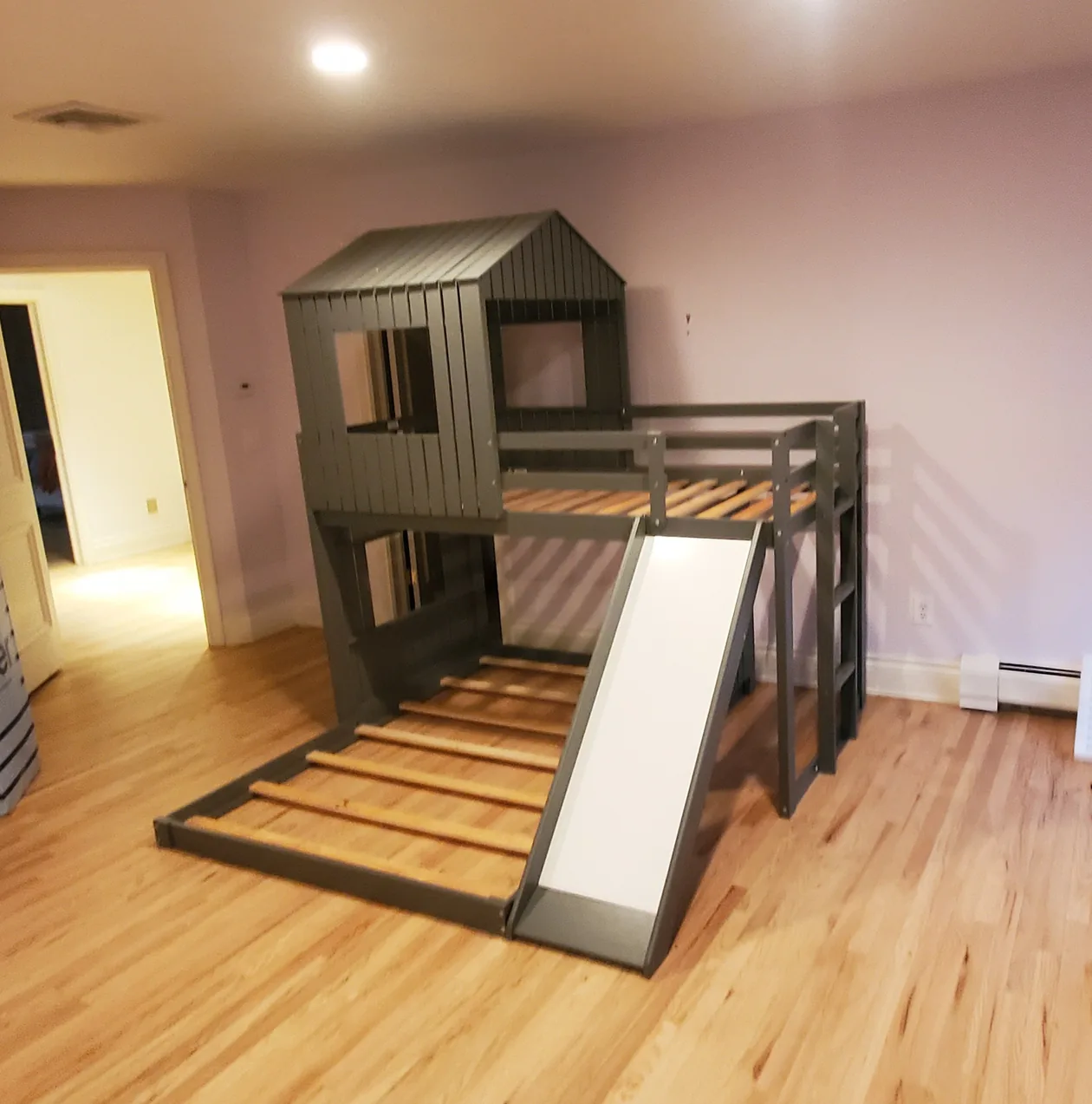 Loft bed with a ladder and slide in a bedroom.