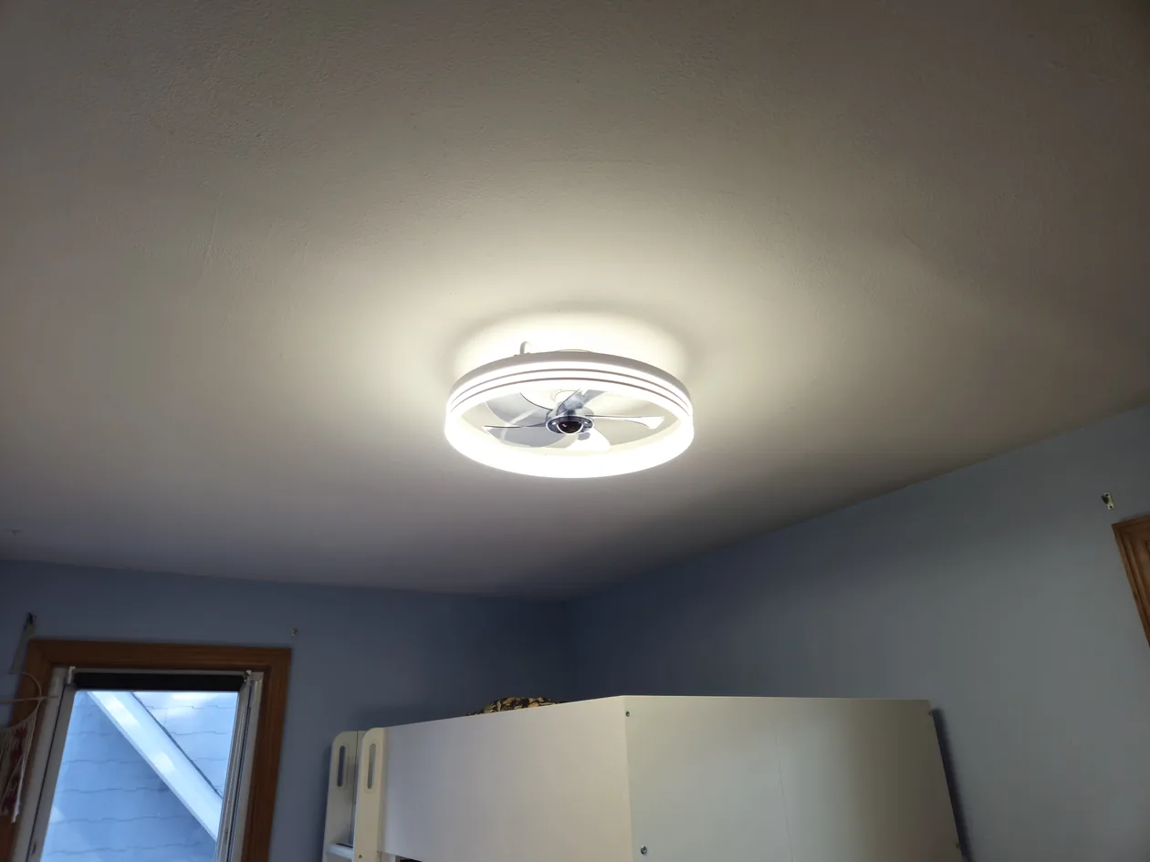 Round illuminated ceiling light in a bedroom.