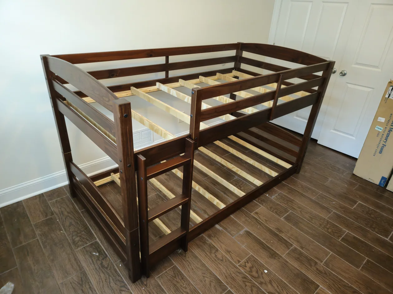 Dark wood bunk bed with a ladder in a bedroom.