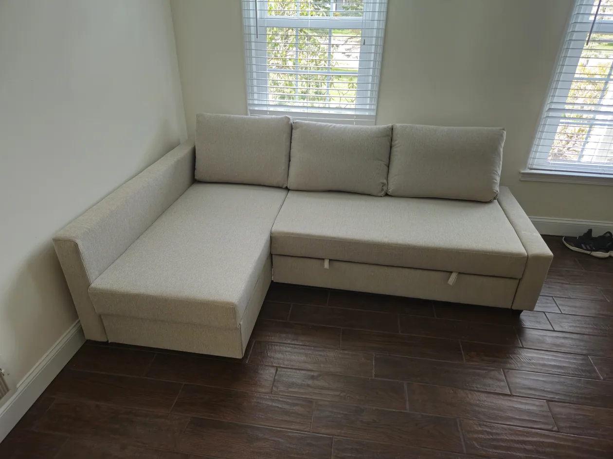 Light-colored sectional sofa below two windows.