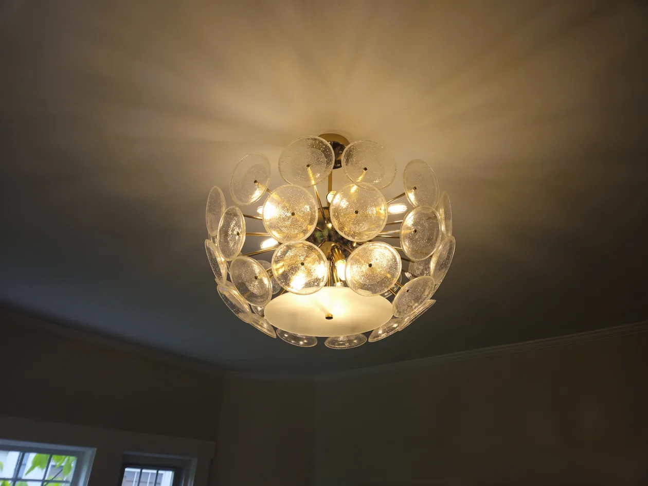 Round crystal ceiling light illuminated against a dark ceiling.