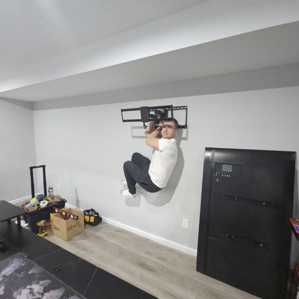 Person working at a wall mount beside a television.