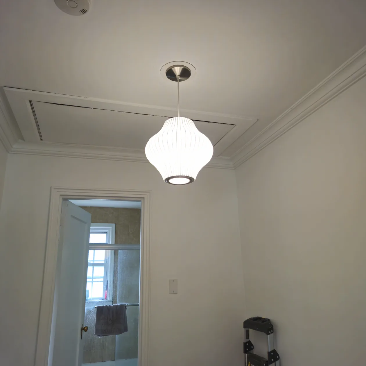 White pendant light hanging from the ceiling in a room.