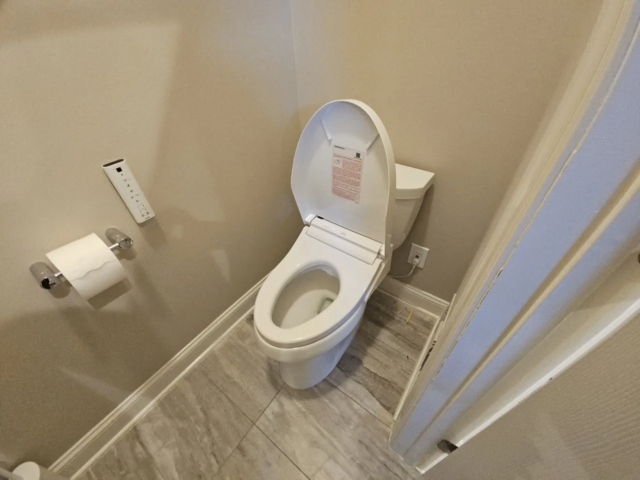 White toilet beside a tiled floor and bathroom accessories.