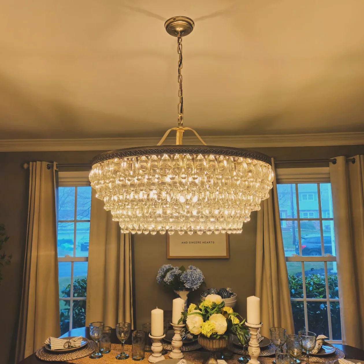 Crystal chandelier above a dining table with flowers.