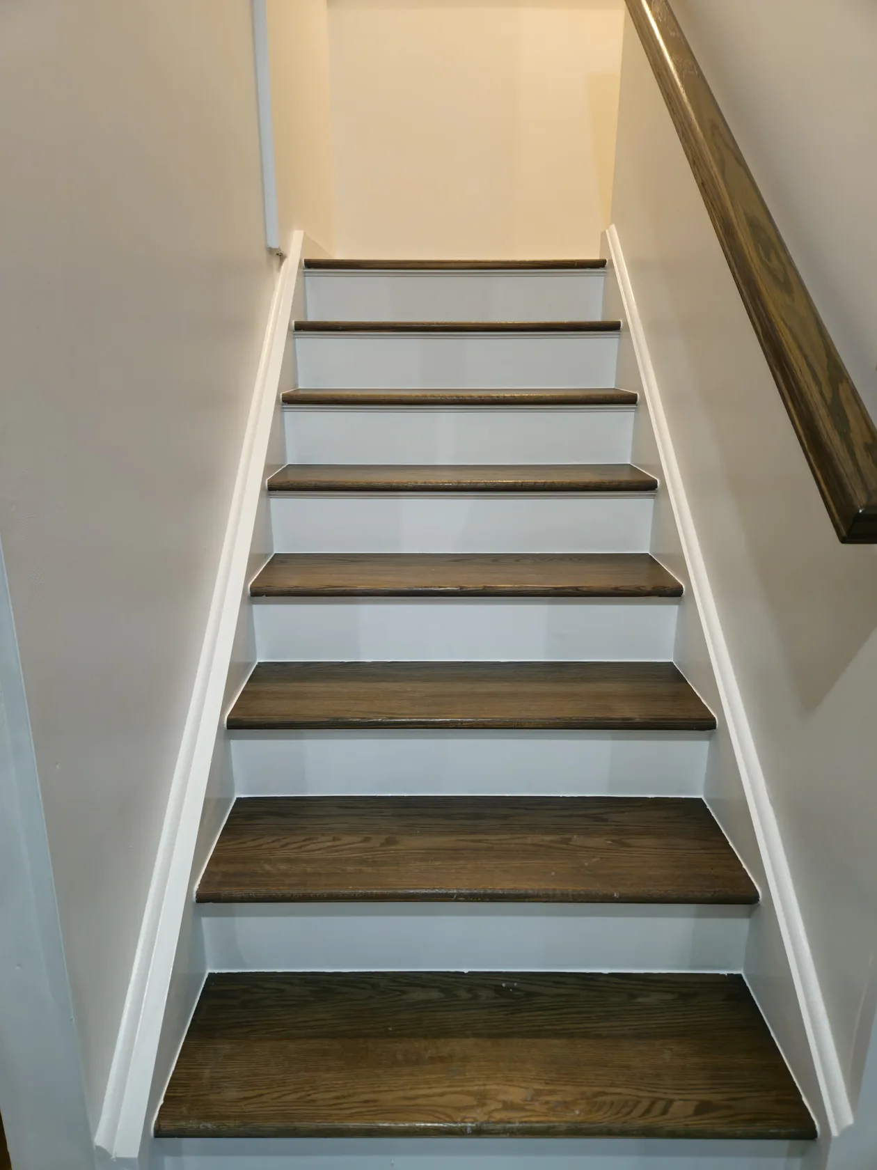Interior staircase with dark wood treads and white risers, viewed from below.